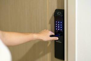 Hand using smart digital door lock while open or close the door at home or apartment. NFC Technology, Fingerprint scan, keycard, PIN number, smartphone, electrical and contactless lifestyle concepts photo