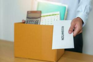 Resignation, Layoff, Unemployment, Dismiss, Job quit, Jobless and Farewell concept. Businessman holding letter of Resign contract with documents cardboard box at office photo