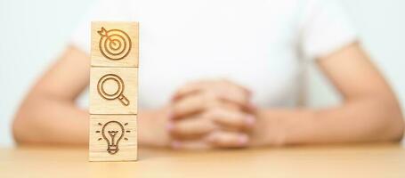 Woman hand holding dartboard above magnifying and Lightbulb icon block. business planning process, goal, vision, strategy, target, mission, action, research, teamwork and idea concept photo