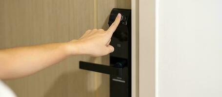 Hand using fingerprint scan for smart digital door lock while open or close the door at home or apartment. NFC Technology, keycard, PIN number, smartphone and contactless lifestyle concepts photo