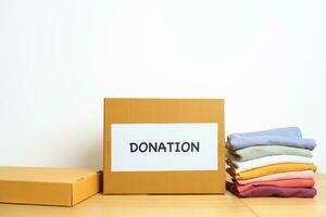 Donation, Charity, Volunteer, Giving and Delivery Concept. Clothes with Donation box at home or office for support and help poor, refugee and homeless people. Copy space for text photo