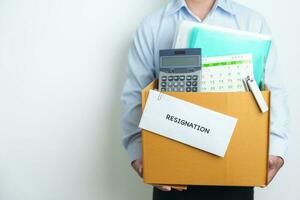 Resignation, Layoff, Unemployment, Dismiss, Job quit, Jobless and Farewell concept. Businessman holding letter of Resign contract with documents cardboard box at office photo