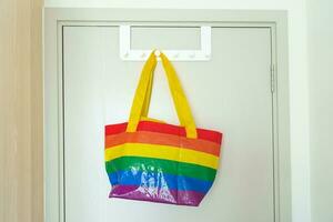 LGBT pride month concept or LGBTQ or LGBTQIA,Eco friendly bag with rainbow color hanging on the door. photo