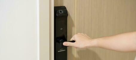 Hand using smart digital door lock while open or close the door at home or apartment. NFC Technology, Fingerprint scan, keycard, PIN number, smartphone, electrical and contactless lifestyle concepts photo