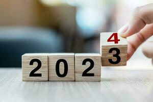 hand flipping block 2023 to 2024 text on table. Resolution, strategy, plan, goal, motivation, reboot, business and New Year holiday concepts photo