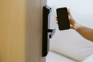 Hand using smartphone for open digital door lock at home or apartment. NFC Technology, Fingerprint scan, keycard, PIN number, smartphone, electrical and contactless lifestyle concepts photo