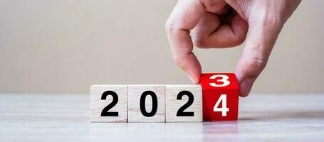 hand flipping block 2023 to 2024 text on table. Resolution, strategy, plan, goal, motivation, reboot, business and New Year holiday concepts photo