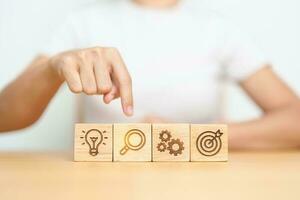 Woman hand pointing magnifying with lightbulb  dartboard and Gear icon block. thinking, business planning process, goal, strategy, target, mission,  vision, action, research, teamwork and idea concept photo