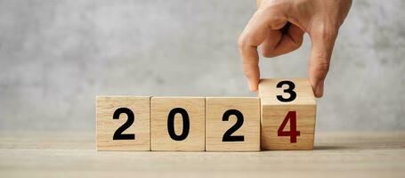 hand flipping block 2023 to 2024 text on table. Resolution, strategy, plan, goal, motivation, reboot, business and New Year holiday concepts photo