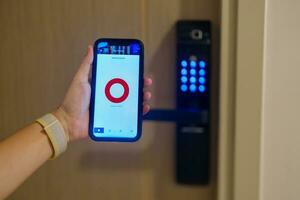 Hand using smartphone for close digital door lock at home or apartment. NFC Technology, Fingerprint scan, keycard, PIN number, smartphone, electrical and contactless lifestyle concepts photo