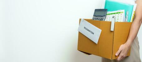 Resignation, Layoff, Unemployment, Dismiss, Job quit, Jobless and Farewell concept. Businesswoman holding letter of Resign contract with documents cardboard box at office photo