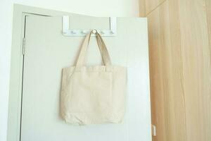 Eco friendly bag hanging on the door. Canvas Shopping tote bag. Zero waste, Reusable, Say No Plastic, Sustainability, World Environment day and Earth day concept photo
