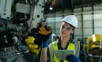 A female engineer installs a program on a robotics arm in a robot warehouse. And test the operation before sending the machine to the customer. photo