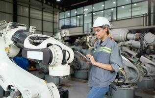 A female engineer installs a program on a robotics arm in a robot warehouse. And test the operation before sending the machine to the customer. photo