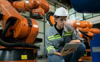 A female engineer installs a program on a robotics arm in a robot warehouse. And test the operation before sending the machine to the customer. photo