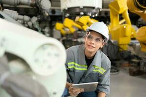 A female engineer installs a program on a robotics arm in a robot warehouse. And test the operation before sending the machine to the customer. photo