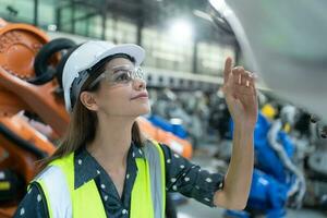 A female engineer installs a program on a robotics arm in a robot warehouse. And test the operation before sending the machine to the customer. photo