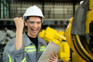 In the robots warehouse, Female engineer happily with updating software and calibrating a robotics arm. photo