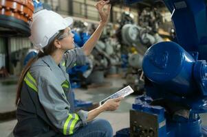 A female engineer installs a program on a robotics arm in a robot warehouse. And test the operation before sending the machine to the customer. photo