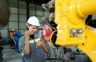 In the robots warehouse, Female engineer happily with updating software and calibrating a robotics arm. photo