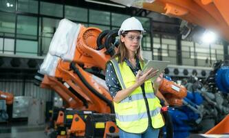 A female engineer installs a program on a robotics arm in a robot warehouse. And test the operation before sending the machine to the customer. photo