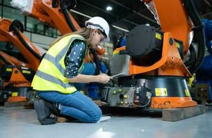 hembra técnico inspeccionando y reparando robótica brazo en robots hangar y prueba el operación de el máquina después siendo usado para un mientras, como bien como actualización el software y calibración foto