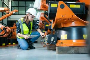 hembra técnico inspeccionando y reparando robótica brazo en robots hangar y prueba el operación de el máquina después siendo usado para un mientras, como bien como actualización el software y calibración foto