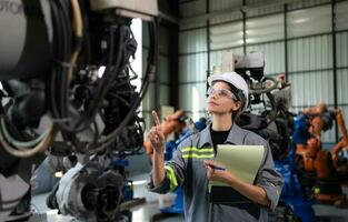A female engineer checking documented items after installing a program on a robotic arm in a robotic warehouse and test the operation photo