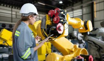 A female engineer installs a program on a robotics arm in a robot warehouse. And test the operation before sending the machine to the customer. photo