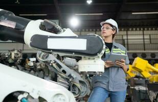 A female engineer installs a program on a robotics arm in a robot warehouse. And test the operation before sending the machine to the customer. photo