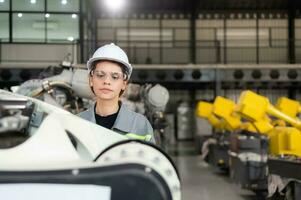 A female engineer installs a program on a robotics arm in a robot warehouse. And test the operation before sending the machine to the customer. photo