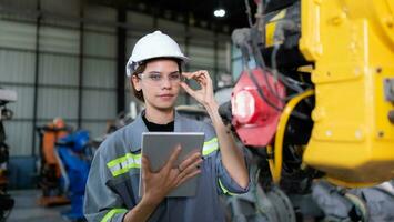 A female engineer installs a program on a robotics arm in a robot warehouse. And test the operation before sending the machine to the customer. photo