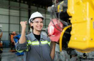 In the robots warehouse, Female engineer happily with updating software and calibrating a robotics arm. photo