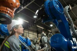 un hembra ingeniero instala un programa en un robótica brazo en un robot depósito. y prueba el operación antes de enviando el máquina a el cliente. foto