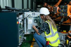 hembra técnico inspeccionando y reparando robótica brazo en robots hangar y prueba el operación de el máquina después siendo usado para un mientras, como bien como actualización el software y calibración foto