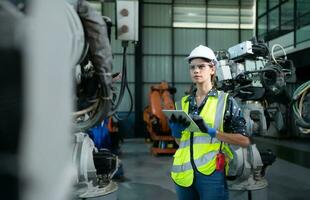 A female engineer installs a program on a robotics arm in a robot warehouse. And test the operation before sending the machine to the customer. photo