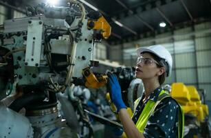 A female engineer installs a program on a robotics arm in a robot warehouse. And test the operation before sending the machine to the customer. photo