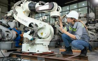 un hembra ingeniero instala un programa en un robótica brazo en un robot depósito. y prueba el operación antes de enviando el máquina a el cliente. foto