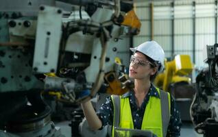 A female engineer installs a program on a robotics arm in a robot warehouse. And test the operation before sending the machine to the customer. photo