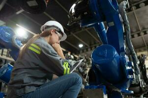 A female engineer installs a program on a robotics arm in a robot warehouse. And test the operation before sending the machine to the customer. photo