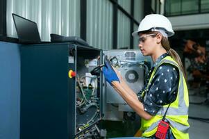 Female Technician Inspecting and repairing robotics arm in robots hangar and test the operation of the machine after being used for a while, as well as updating the software and calibration photo