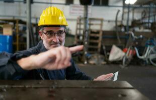 An elderly technician uses a computer to test the operation control of a steel punching machine. photo