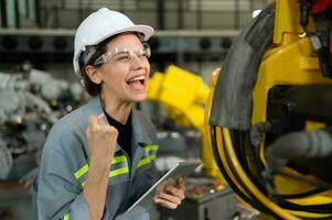 In the robots warehouse, Female engineer happily with updating software and calibrating a robotics arm. photo