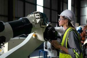 en el robots depósito, hembra ingeniero felizmente con actualización software y calibrando un robótica brazo. foto