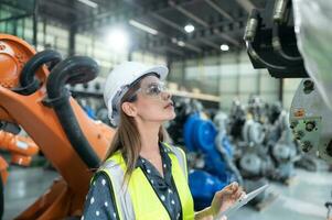 A female engineer installs a program on a robotics arm in a robot warehouse. And test the operation before sending the machine to the customer. photo