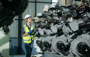 A female engineer installs a program on a robotics arm in a robot warehouse. And test the operation before sending the machine to the customer. photo