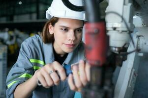 Female Technician Inspecting and repairing robotics arm in robots hangar and test the operation of the machine after being used for a while, as well as updating the software and calibration photo