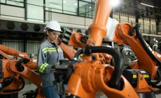 After installing a program on the robotic arm, a female engineer with a robotic arm controller performs a test run. photo