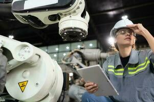 A female engineer installs a program on a robotics arm in a robot warehouse. And test the operation before sending the machine to the customer. photo