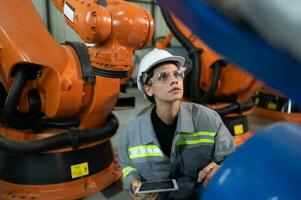 A female engineer installs a program on a robotics arm in a robot warehouse. And test the operation before sending the machine to the customer. photo
